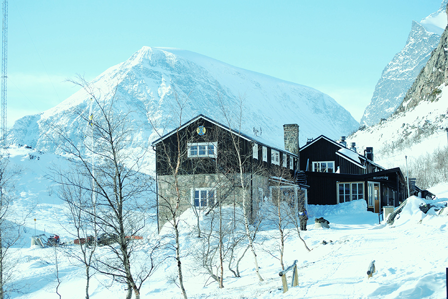 STF Kebnekaise fjällstation under vintersäsong med snö och blå himmel