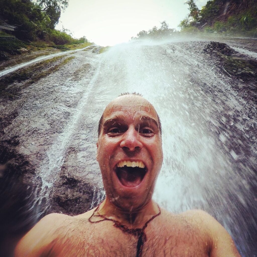 Fredrik Sträng poserar glad i ett vattenfall i Nepal